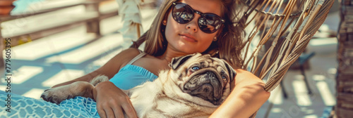 A woman in sunglasses lounges with a pug in a hammock, showcasing a moment of leisure and companionship