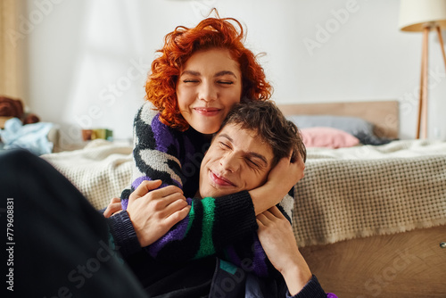 stylish cheerful woman with red hair spending time with her boyfriend and hugging him lovingly