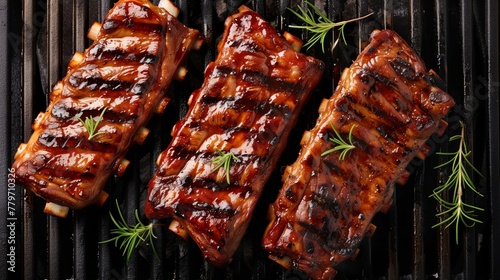 Juicy barbecued ribs with sauce on a grill, garnished with rosemary