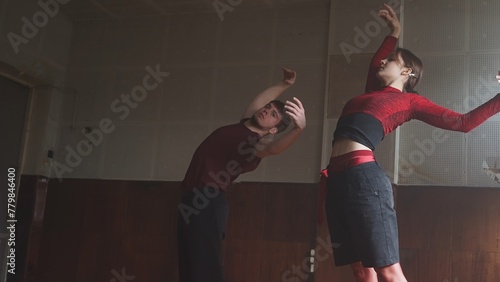 Professional dancers performing dance show. Young man and woman contemporary dancers perform modern choreography elements in old hall, full length.