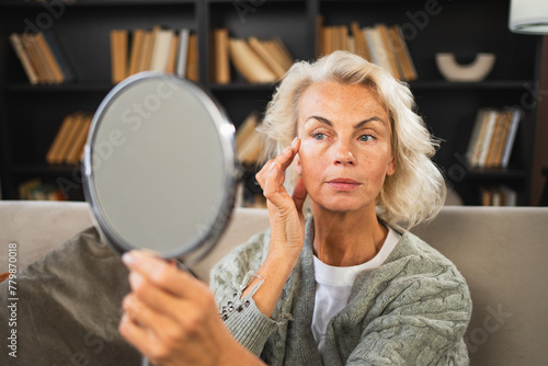 Love yourself. Beautiful old mature woman enjoying mirror reflection. Senior adult older lady looking at mirror confident happy on sofa at home. Woman doing daily morning beauty routine. Self love