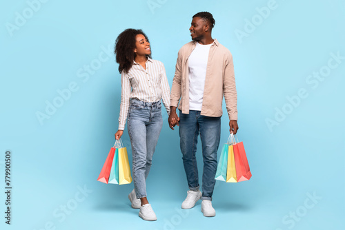 Couple walking and holding shopping bags on blue background