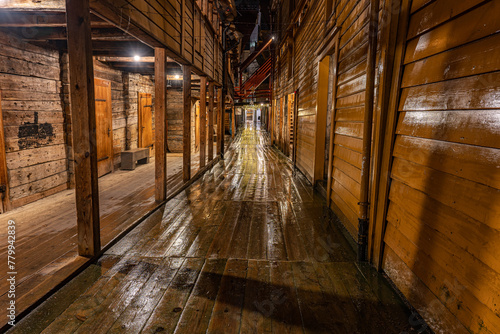die regennassen Holzhäuser im alten Stadtteil Brygge, Bergen in Norwegen bei Regen, Spiegelung der Beleuchtung am regennassen Holz