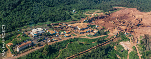 aerial landscape view around a Bauxite mining plant located within a green forest with ocean in the background and orange surface around the mine