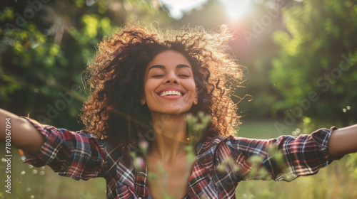 Portrait of a free happy latin american woman with open arms enjoying life in meadows and nature background , young joyful latina female with good mental health