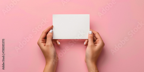 Woman's hands pwith manicure resenting folded blank paper sheet or booklet, against pastel pink background, Focus on crispness of paper and clean. Mock up adv advertisement concept