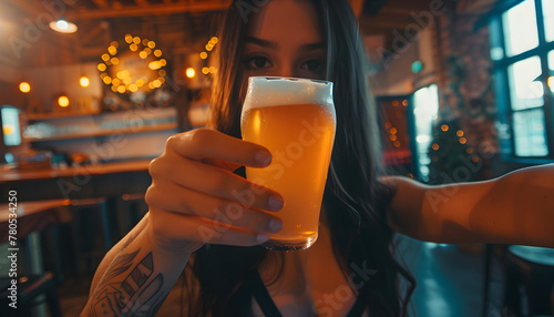 A girl holds a beer in her hands and make selfie in a craft pub.