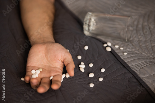 Hand, white pills, glass of water. Man lying bed. suicide attempt sleeping pills and antidepressants, overdose, heart attack, unconscious, blurry, no face, focus, mental disorders, neural connections