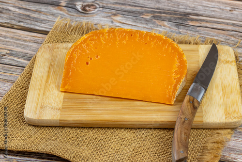 tranche de fromage français : mimolette extra vieille, en gros plan, sur une planche à découper