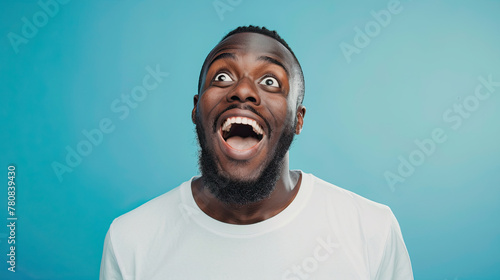 Portrait of a happy and excited man looking up with mouth open on pastel blue background