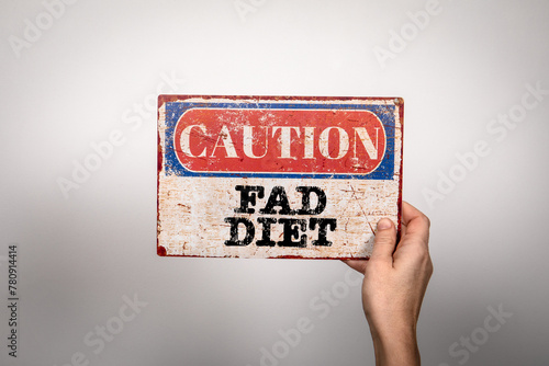 Fad Diet. Metal warning sign in a woman's hand on a white background