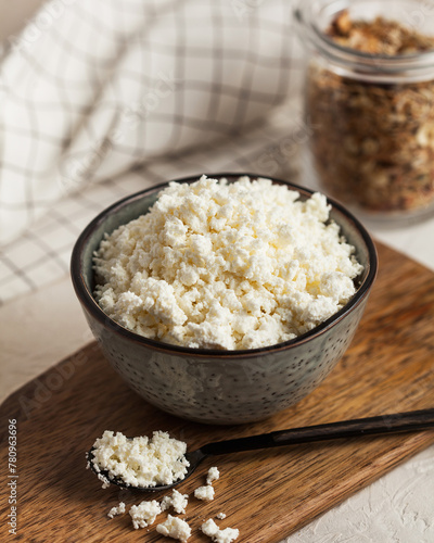 Fresh homemade crumbly cottage cheese in a bowl, farm-fresh produce.