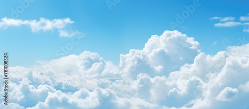 The image shows a distant plane navigating through a serene blue sky adorned with fluffy white clouds