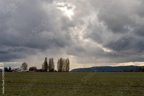 Dramatic sky with early spring storm clouds and rain just before sunset, above and empty farm field, as a nature background 