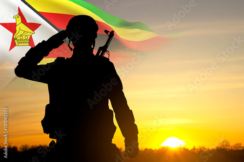 Silhouette of a saluting soldier with Zimbabwe flag against the sunset