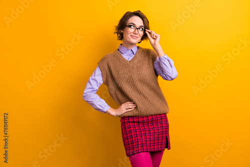 Photo of adorable smart girl dressed knitwear waistcoat touch glasses look at discount empty space isolated on yellow color background