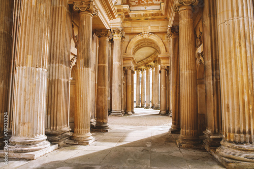 An elegant corridor adorned with intricately designed columns and arches, bathed in soft light and shadow