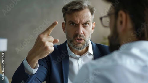 A senior businessman firmly pointing a finger, with a stern expression, in a conversation likely involving a serious matter.