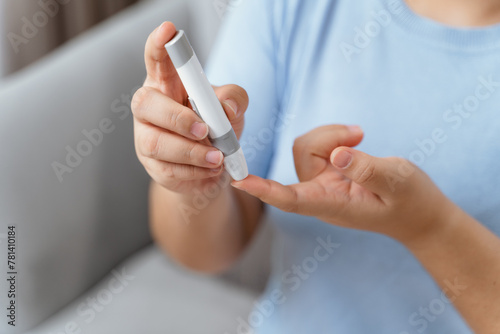 Asian woman using lancet on finger for checking blood sugar level by Glucose meter, diabetes.