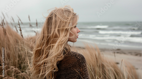 Blonde woman gazing at Scandinavian beach, Denmark coastal landscape. 