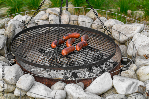 Rumiane chrupiące kiełbaski leżą na ruszcie rozpalonego grilla w ogrodzie 