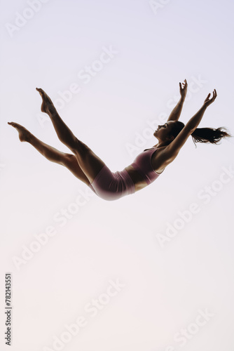 In-flight gymnast: A female acrobatics performer leaps mid-air in a graceful routine