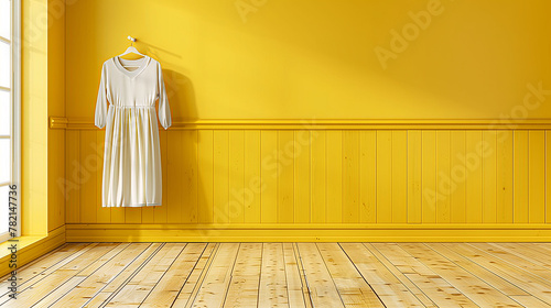 Elegant white dress hanging on a hanger against a vibrant yellow wall with wooden paneling and a sunlit wooden floor, creating a warm, minimalist fashion interior scene.