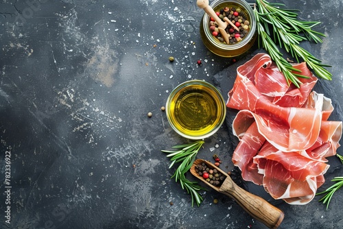 Top view of prosciutto on stone table with olive oil and rosemary Copy space available