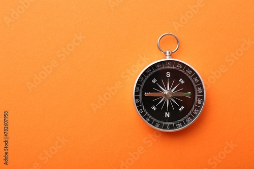 One compass on orange background, top view. Space for text