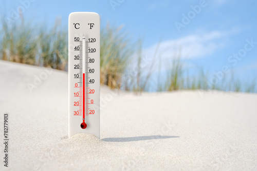 Hot summer day. Celsius and fahrenheit scale thermometer in the sand. Ambient temperature plus 15 degrees