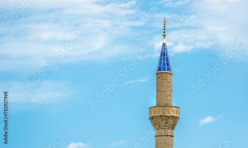 Mosque minaret with blue glass in front of a sunny, cloudless blue sky