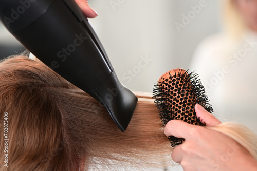 Hair stylist brushing and drying blonde hair with a special technique