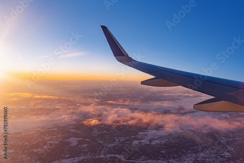 Airplane flying low over snowy mountains and preparing for landing to the airport, view from plane window of wing turbine and skyline