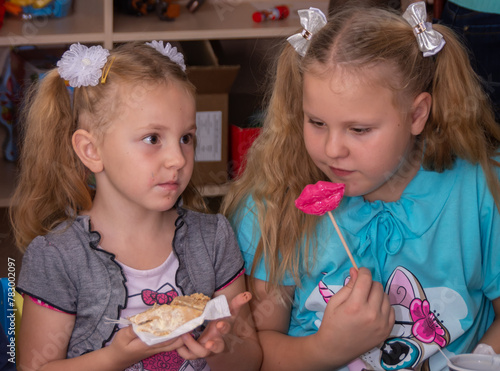 The girls are sitting at the festive table. Sweet treats. Girls eat sweets. 