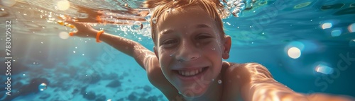 A cheerful young boy taking a selfie while swimming underwater