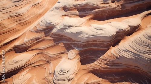 Aerial view of sandstone formations in a desert, with textured patterns carved by wind and water erosion over millennia