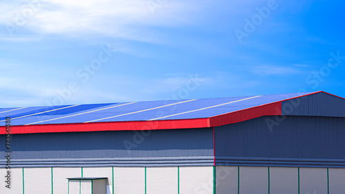 Large rental warehouse building with aluminium steel gable roof against blue sky background
