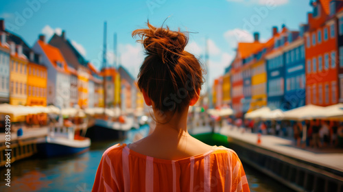 Tourist overlooking colorful Nyhavn harbor in Copenhagen, Denmark.