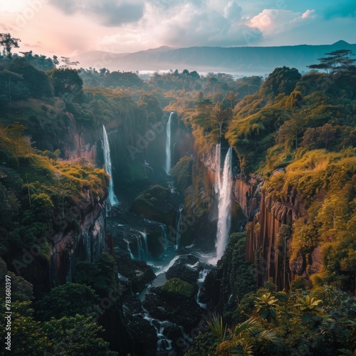 Breathtaking aerial view of a tropical waterfall surrounded by lush forest and cliffs, with mist rising from the cascading water.