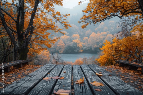 Two oaken benches overlook a calm lake surrounded by trees adorned with vibrant autumn leaves
