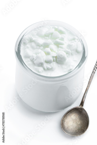 Granular cottage cheese with cream in a glass jar isolated on white