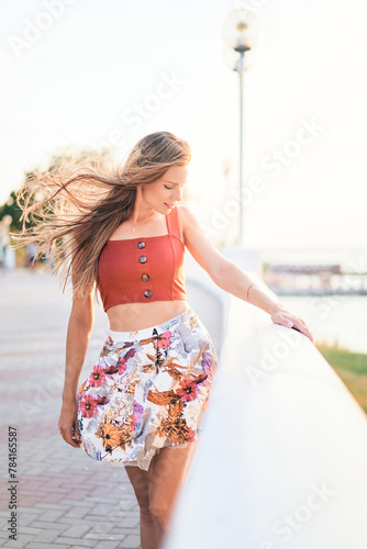 Bright portrait of a young woman walking down the street at sunset