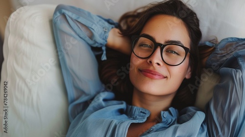 A relaxed and content woman wearing stylish glasses and a blue blouse