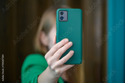 Dziewczyna trzyma w dłoni telefon komórkowy i robi sobie zdjęcie przednim aparatem smartfona