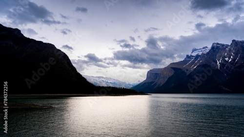 Glacial lake Minnewanka in the Banff national park with snowy mountains against the cloudy sky