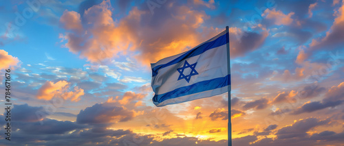 Israel flag waving in the wind against an orange dramatic sunset sky