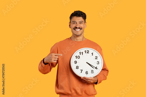 Happy guy with clock showing punctuality on yellow