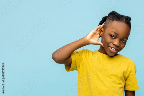 Smiling African American little boy with hand near ear