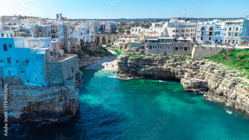 Aerial drone panorama of Polignano a mare, a beautiful city in Puglia, italy, on a sunny day. Visible beach coming to the sea and the old town next to it.