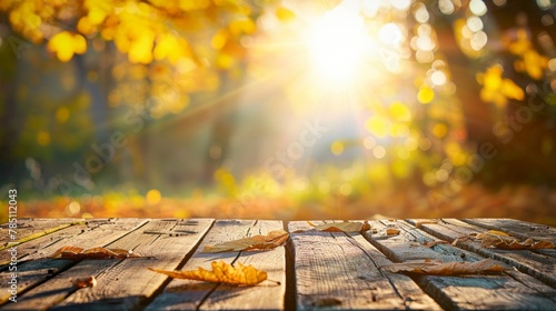 Golden autumn sunlight filters through leaves, casting a warm glow on a wooden path strewn with fallen leaves.